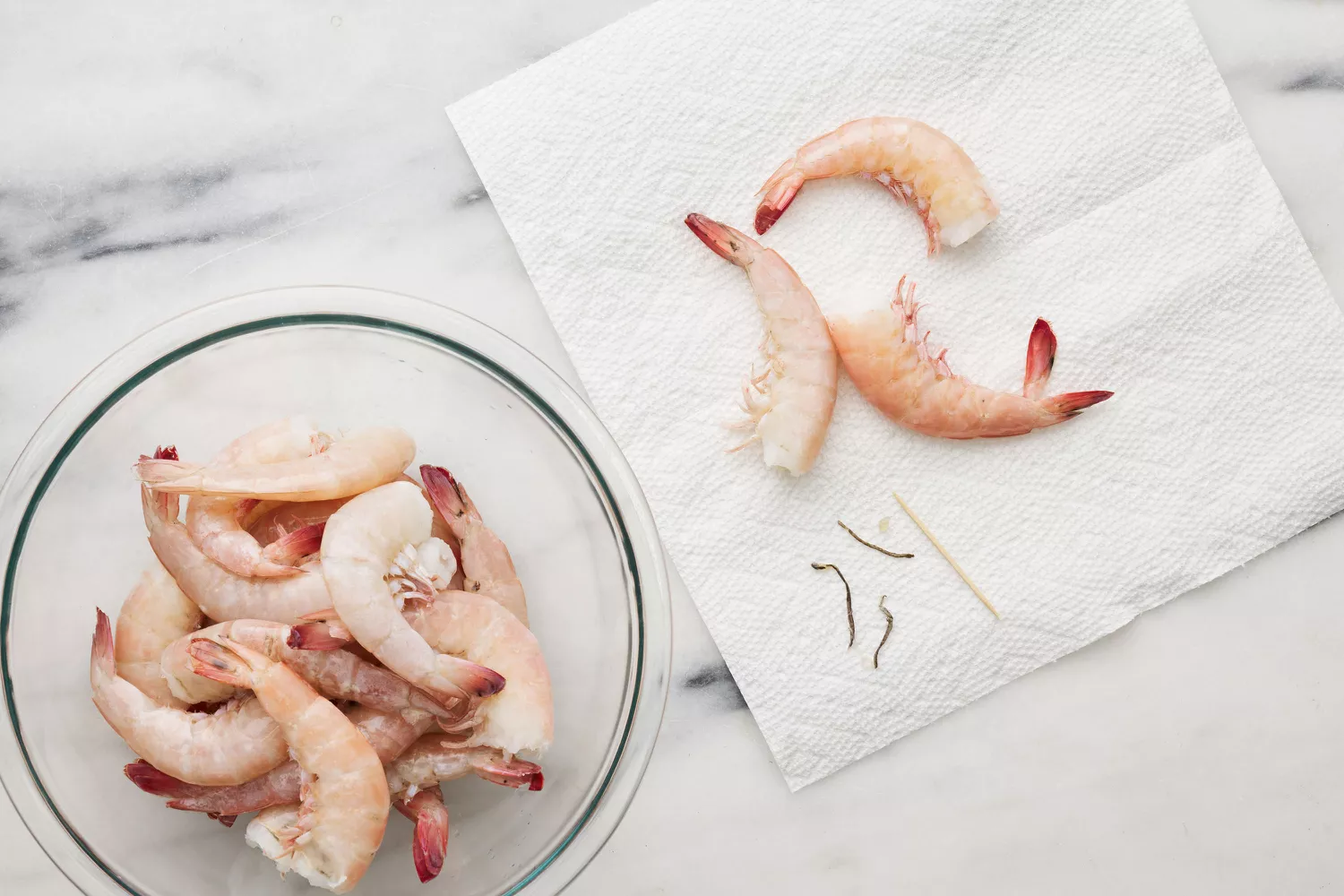Un grand bol de crevettes, avec trois crevettes décortiquées à côté d'un cure-dent