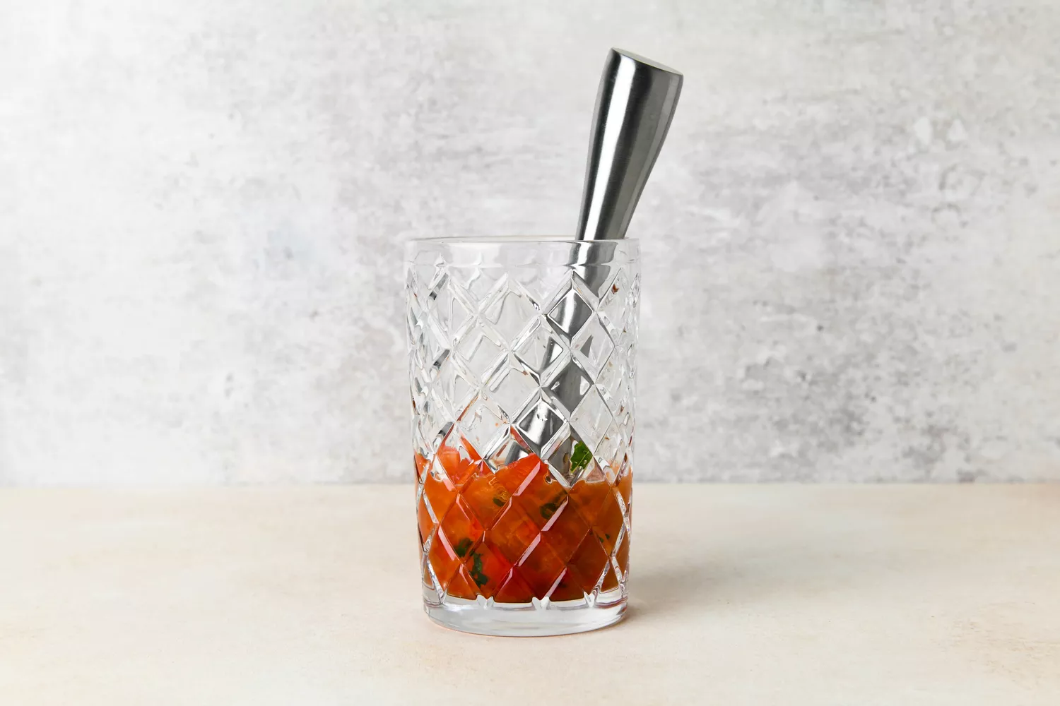 Écraser le basilic et les poivrons dans un shaker à cocktail