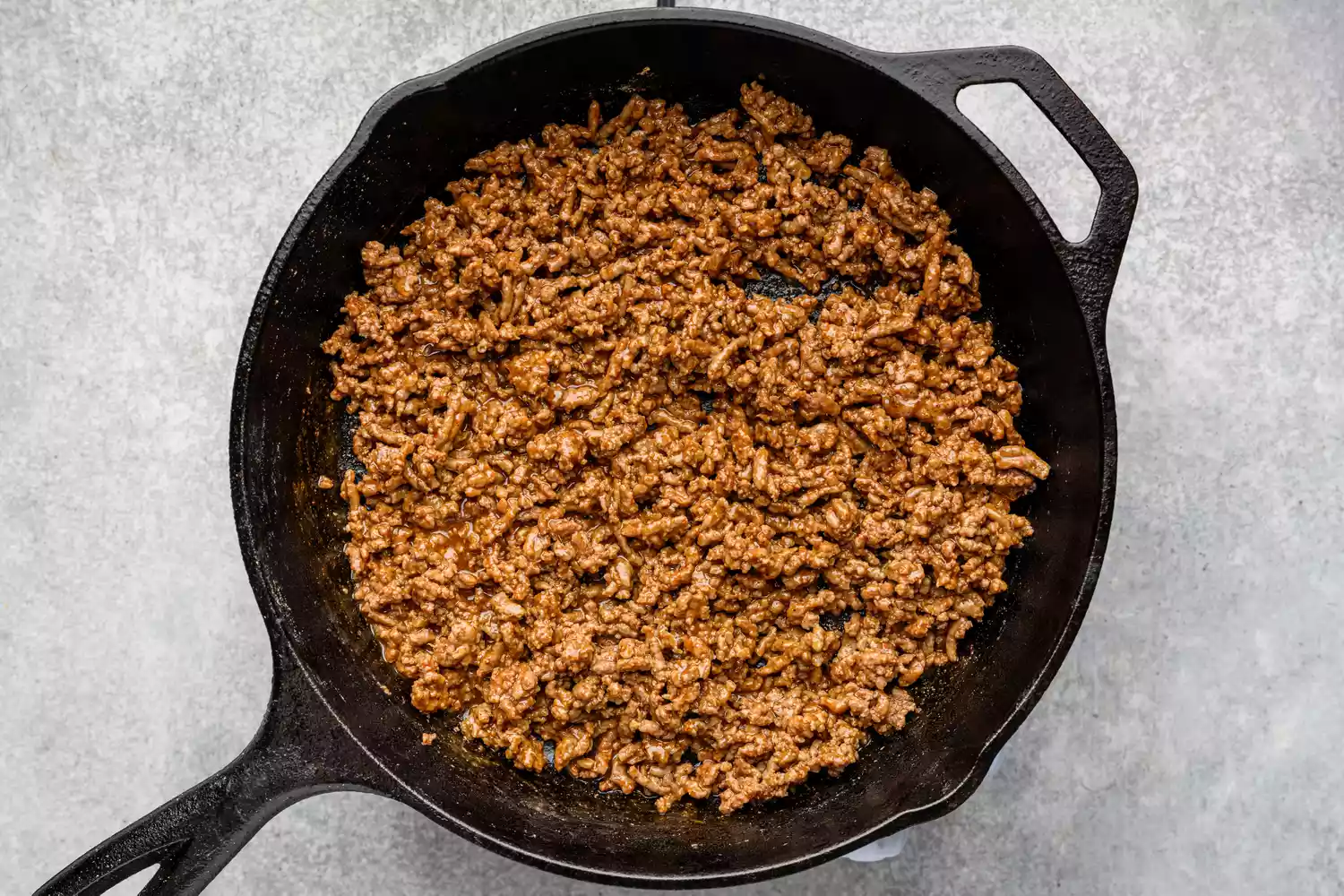 Une grande poêle de boeuf haché cuit avec de l'eau et des épices à taco