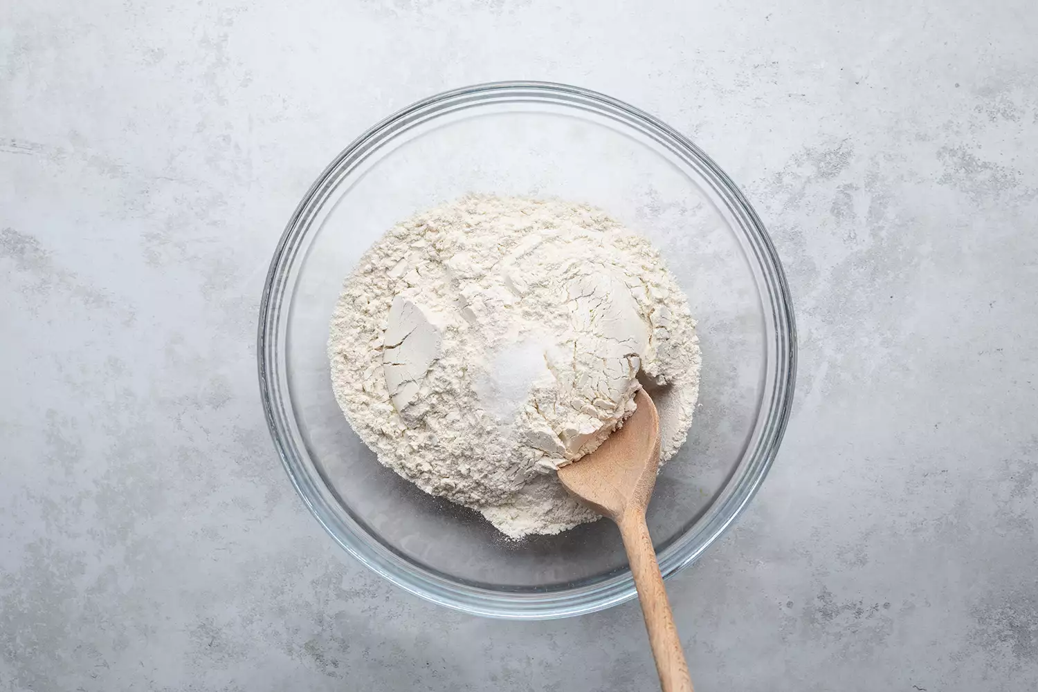 Farine et sel dans un bol en verre avec cuillère en bois