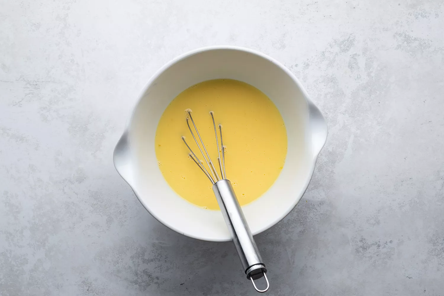 Mélange de lait et d'œufs dans un bol avec un fouet
