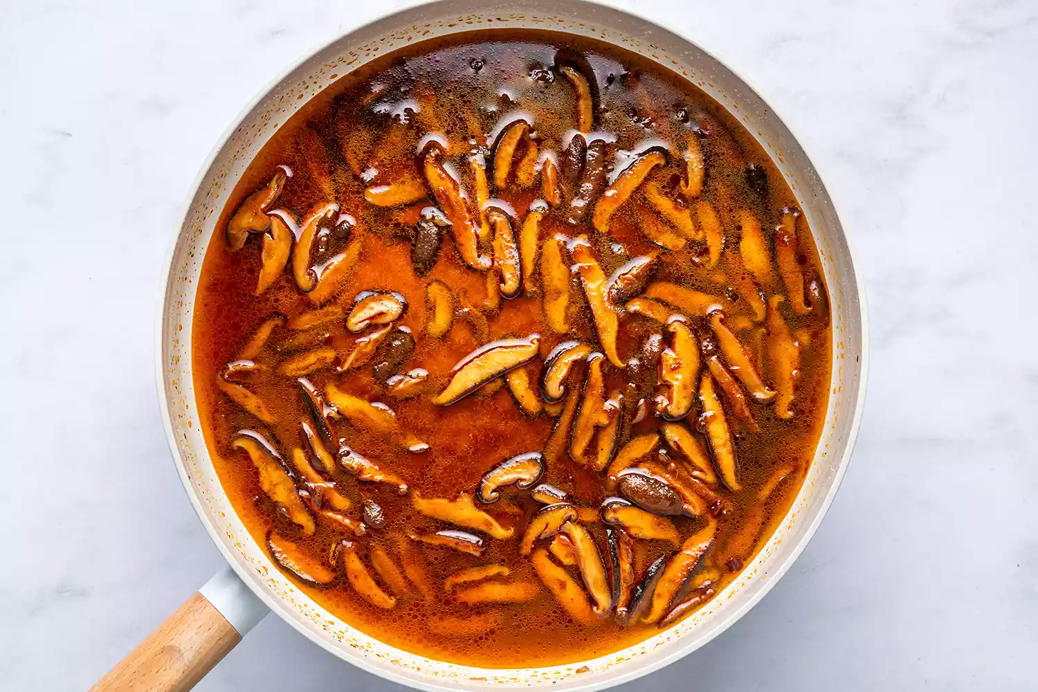 Une poêle avec l'eau de cuisson des pâtes et des champignons