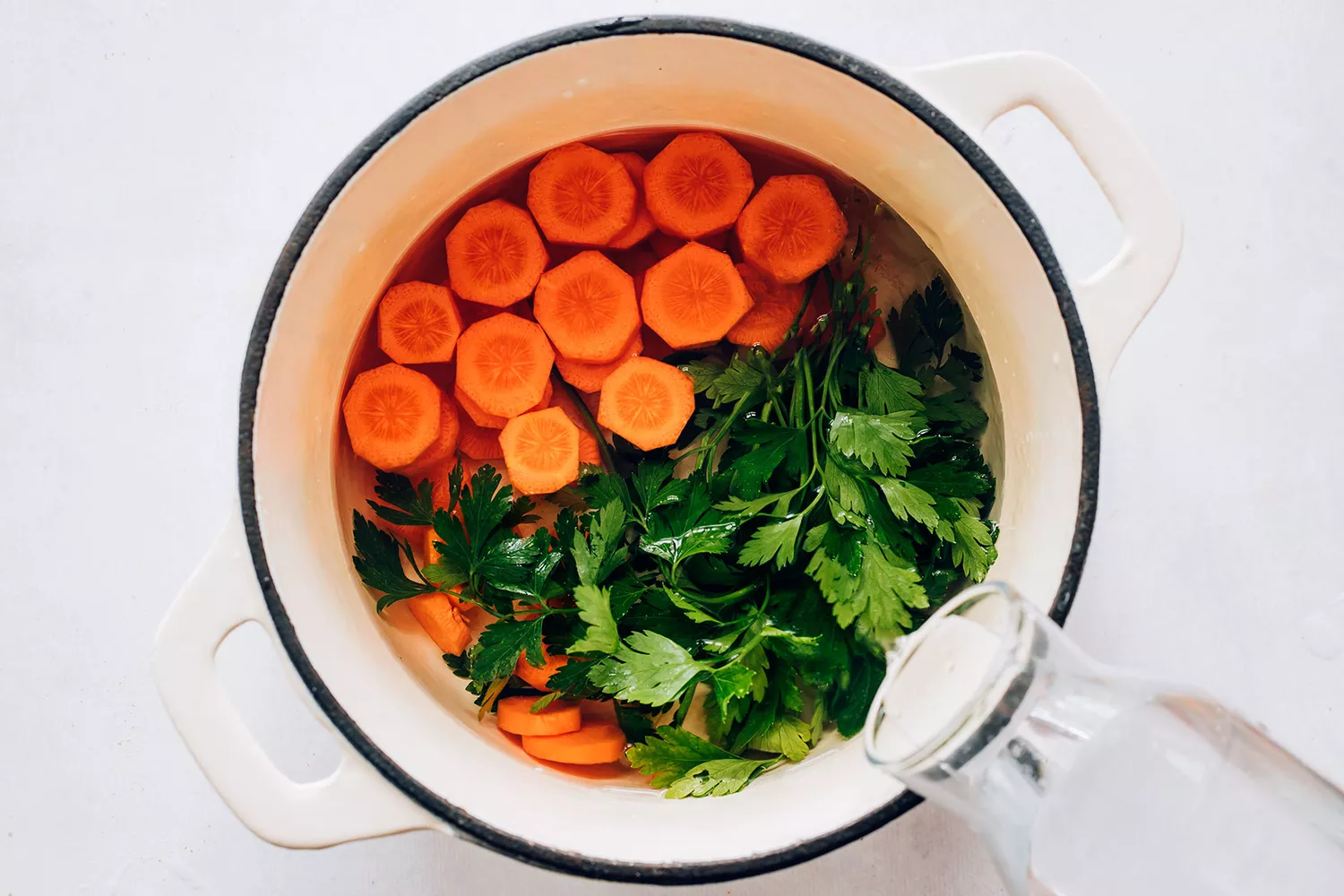 Eau froide, carottes et persil dans une casserole