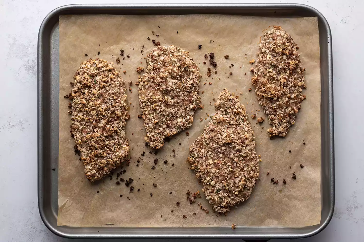 Poulet cuit en croûte d'amande sur une plaque tapissée de papier sulfurisé