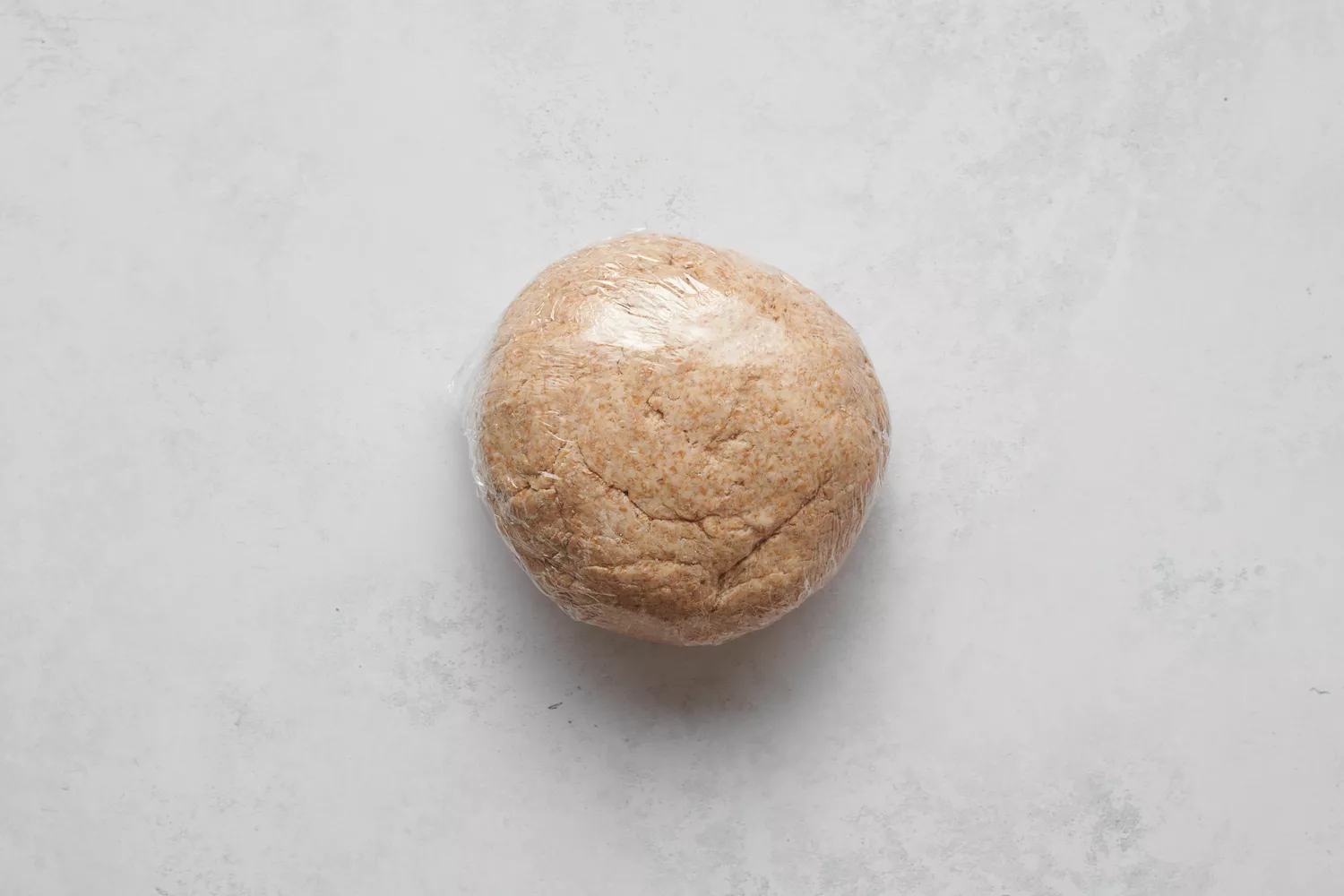 Une boule de pâte pétrie couverte de film plastique