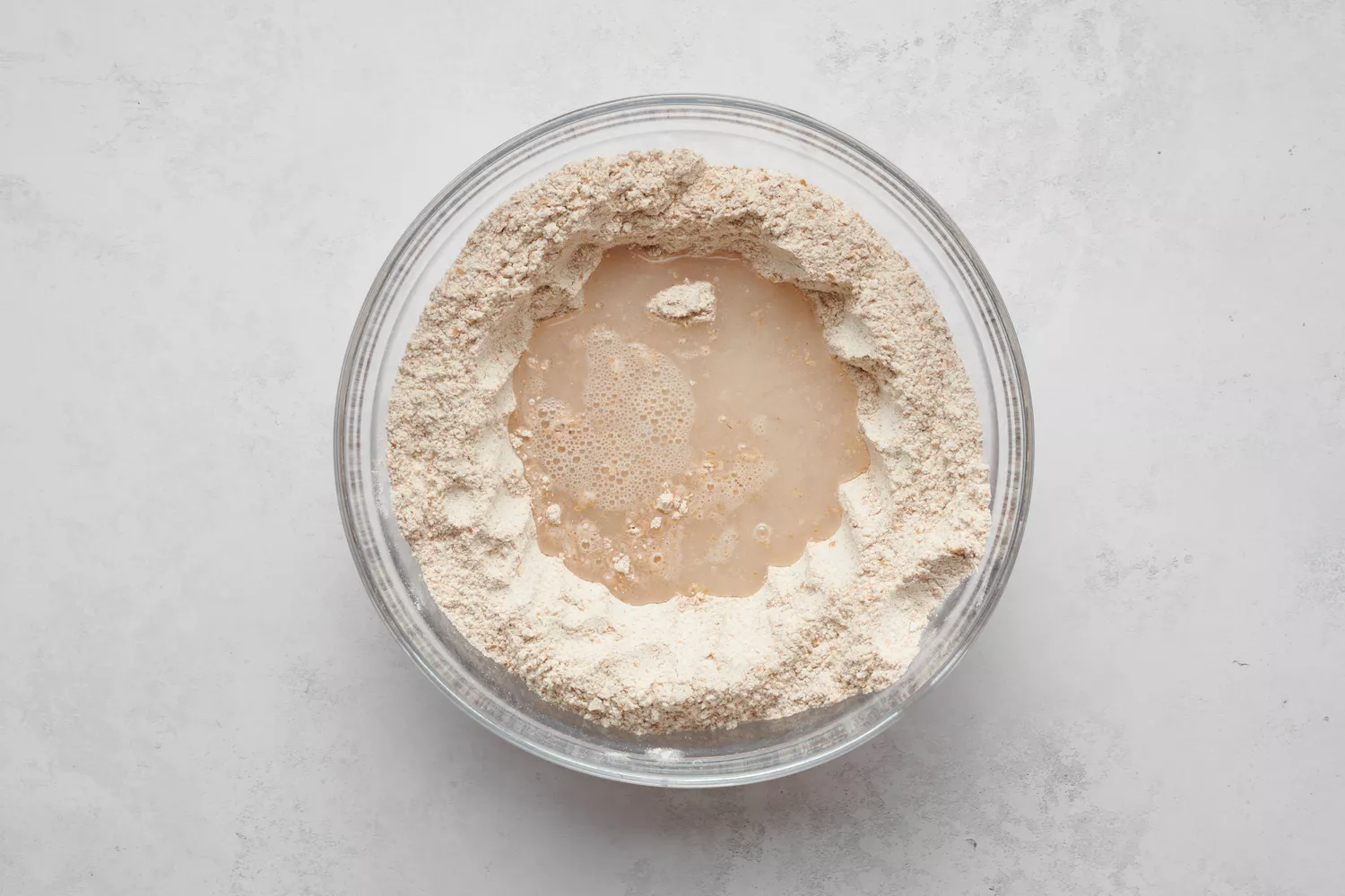 Un bol de mélange de farine avec une fontaine d'eau au milieu