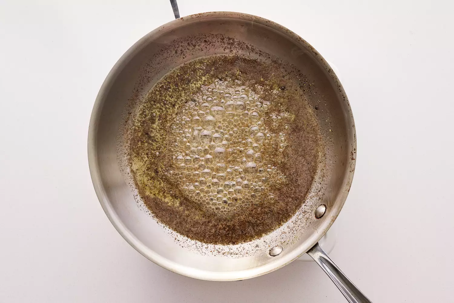 Butter heating in a stainless steel pan.