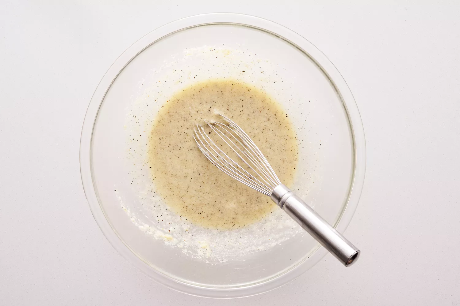 Percorino sauce in a glass bowl with metal whisk.