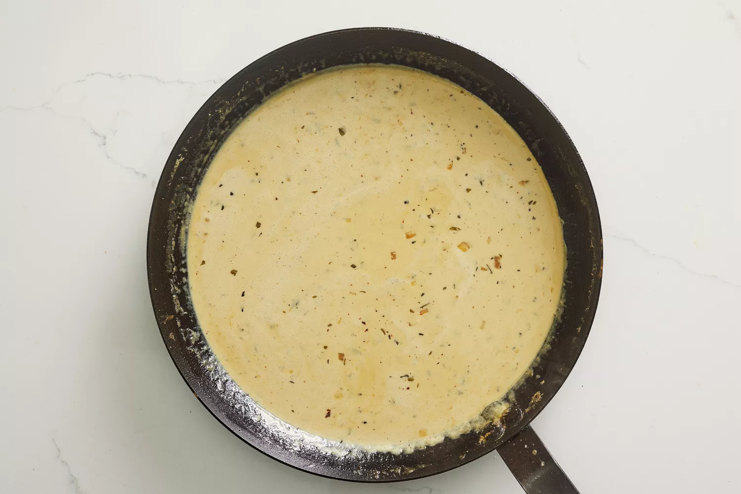 A skillet with creamy, dijon-parmesan sauce